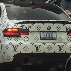 the back end of a white car covered in louis vuitton letters and stars