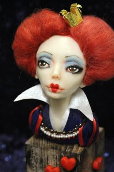 a close up of a doll with red hair and blue eyes wearing a crown on it's head