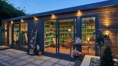 a small house with lots of windows and lights on it's side walk way