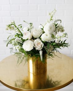 a gold vase with white flowers on a table