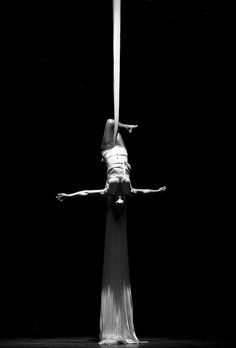 a woman is doing acrobatic tricks on a pole in black and white