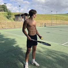 a shirtless man holding a tennis ball and racquet