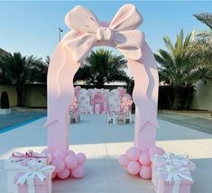 pink and white wedding arch decorated with balloons, bows and presents for the bride and groom