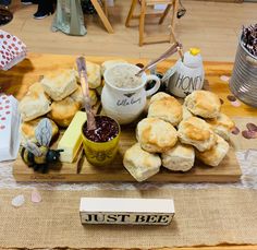 a wooden tray filled with pastries and other items on top of a table next to a sign that says just bee