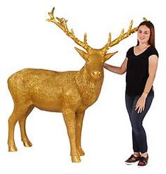 a woman standing next to a golden deer statue