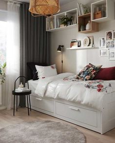 a bed room with a neatly made bed and lots of shelves on the wall above it