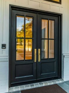 two black double doors on the side of a white building