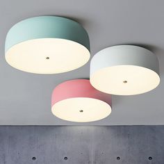 three circular lights hanging from the ceiling above a bed in a room with concrete walls