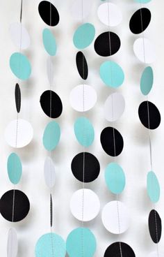 black, white and blue paper circles are hanging from a string that is hung on the wall