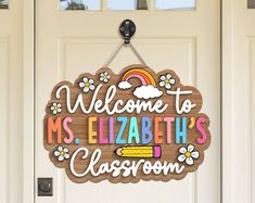 a welcome sign hanging from the front door of a classroom with flowers and rainbows