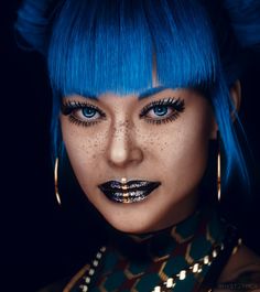 a woman with blue hair and piercings on her face