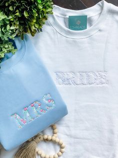 a t - shirt with the word girls on it next to a plant and beads