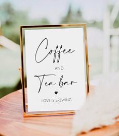 a sign that says coffee and tea bar on top of a wooden table with feathers