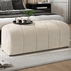 a white ottoman sitting on top of a rug next to a bed