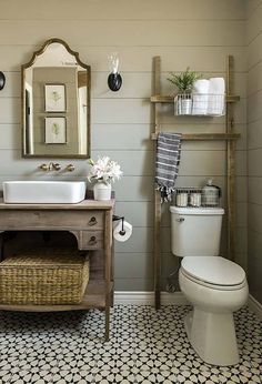 a white toilet sitting next to a sink in a bathroom under a mirror and wooden shelf