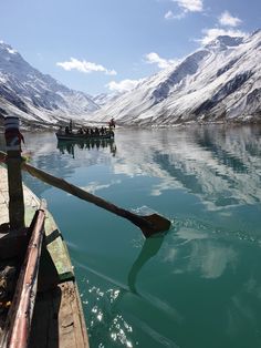 a boat floating on top of a lake next to snow covered mountains