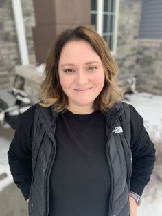 a woman standing in front of a house with her hands on her hips and looking at the camera