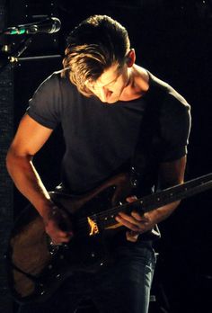 a young man playing an electric guitar on stage