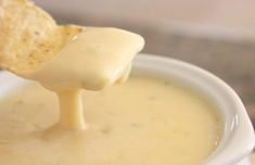 a white bowl filled with soup and a tortilla chip sticking out of it