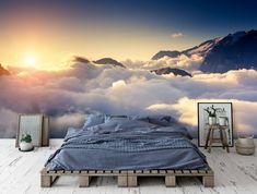 a bed sitting on top of a wooden floor under a sky filled with clouds