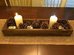 pine cones and candles in a wooden tray on a table