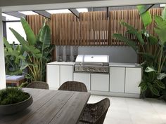 an outdoor kitchen with table, grill and potted plants