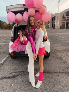 two girls standing in front of a car with pink balloons