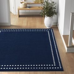 a blue rug with white polka dots on it in a hallway next to stairs and a potted plant