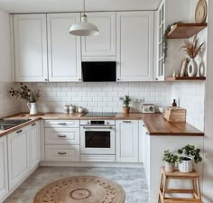 the kitchen is clean and ready for us to use it's white cabinets, wood counter tops, and wooden stools