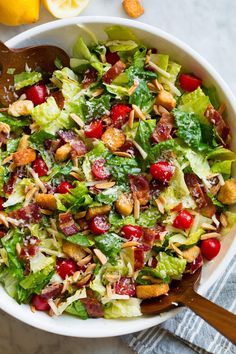 a salad with cranberries, almonds and lettuce in a white bowl