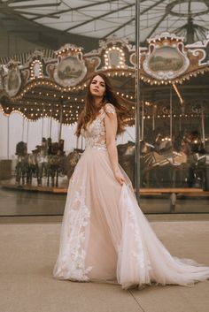 a woman standing in front of a merry go round at an amusement park wearing a wedding dress