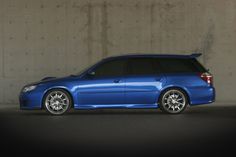 a blue car parked in front of a concrete wall