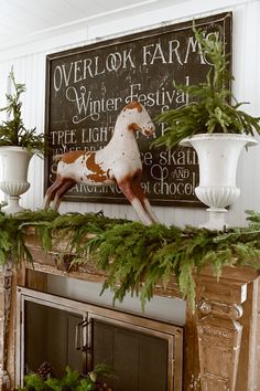 a fireplace mantel decorated with greenery and a horse figurine