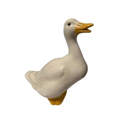 a white ceramic duck with yellow feet on a white background