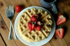 a waffle topped with strawberries on top of a white plate next to a fork