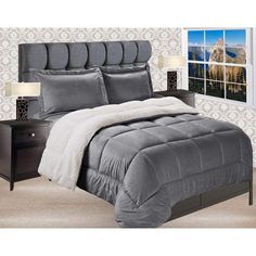 a bed with grey comforter and pillows in a room