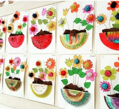 art work displayed on white board with flowers in vases and other artwork hanging on the wall