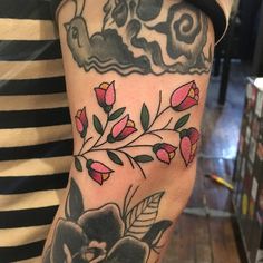 a woman's arm with flowers and clouds on it