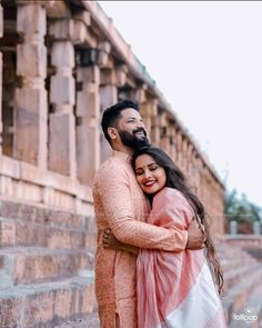 a man and woman hugging each other in front of an old building