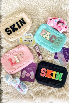 four personalized makeup bags sitting on top of a fluffy white blanket next to each other