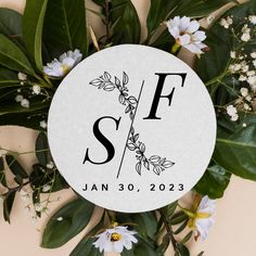 a white circle with the letter f on it surrounded by flowers