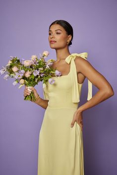 a woman in a yellow dress holding flowers