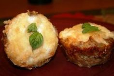 two muffins on a red plate topped with cheese and basil