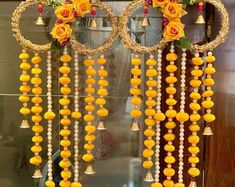 an arrangement of yellow flowers and beads hanging from a wall in front of a mirror