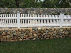 a white picket fence next to a stone wall