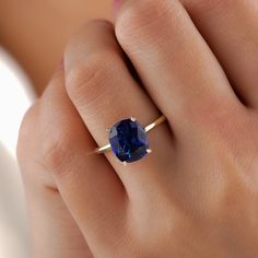 a woman's hand with a gold ring and a blue sapphire stone on it