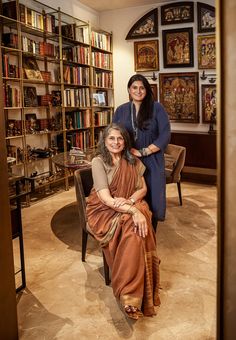 two women sitting on chairs in front of bookshelves