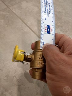 a hand holding a measuring tape over a golden fire hydrant