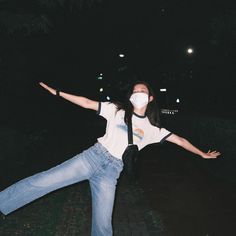 a woman with her arms outstretched in the air while wearing jeans and a t - shirt