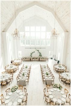 a large room with tables, chairs and chandeliers set up for an event